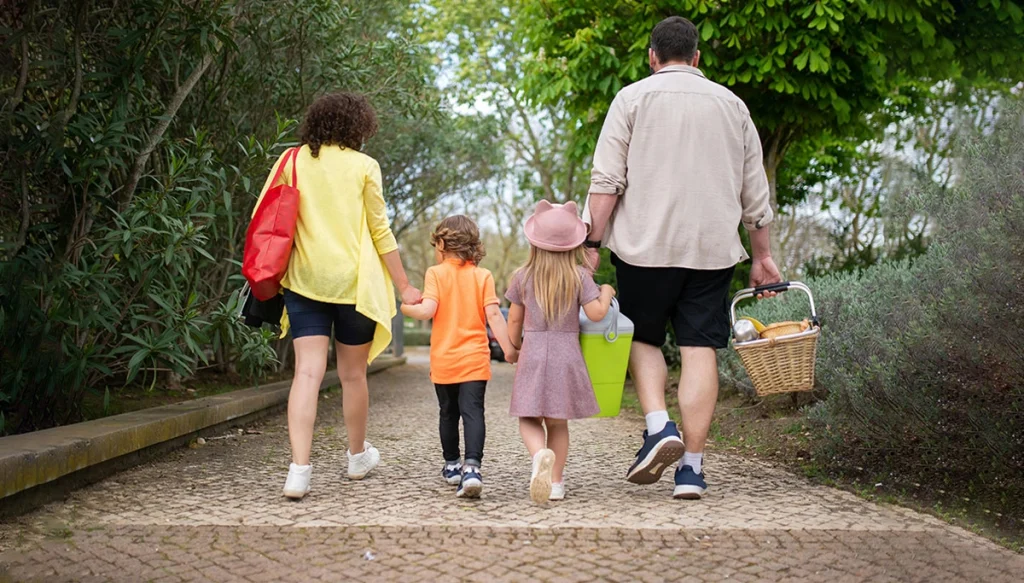 children with parents holding hands walking in a wooded park